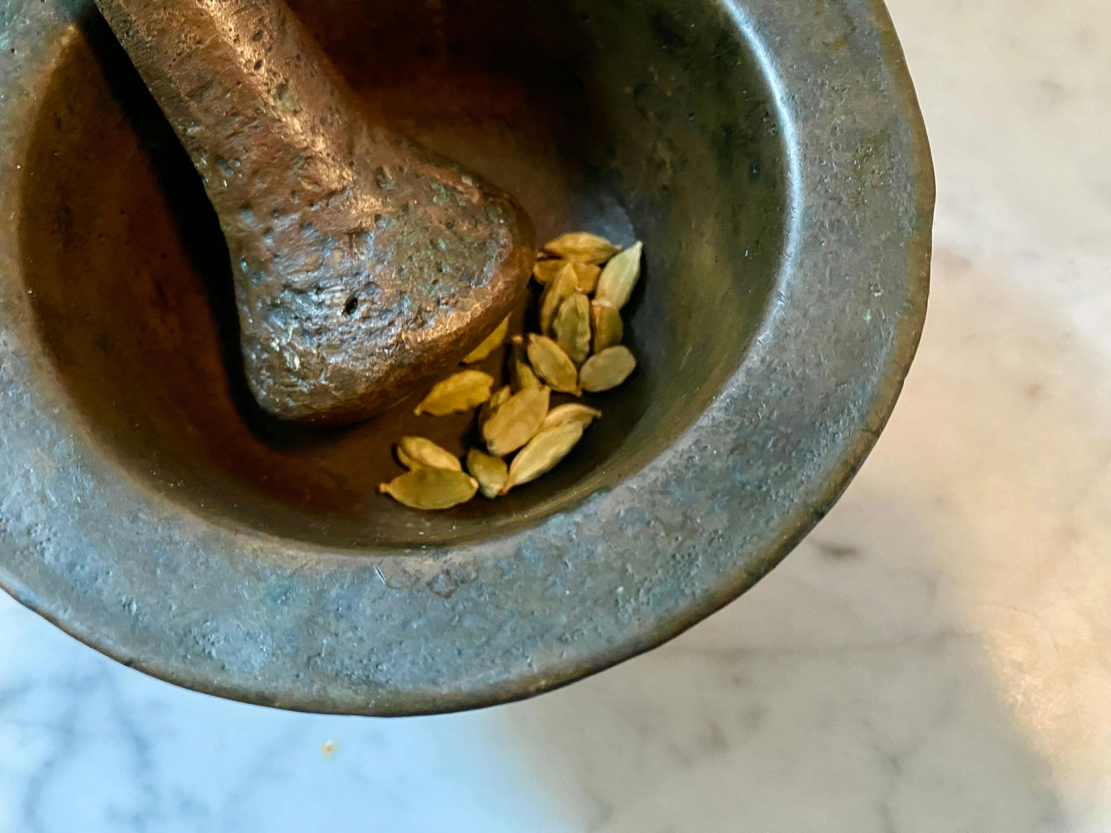 pestle and mortar with whole cardamon pods