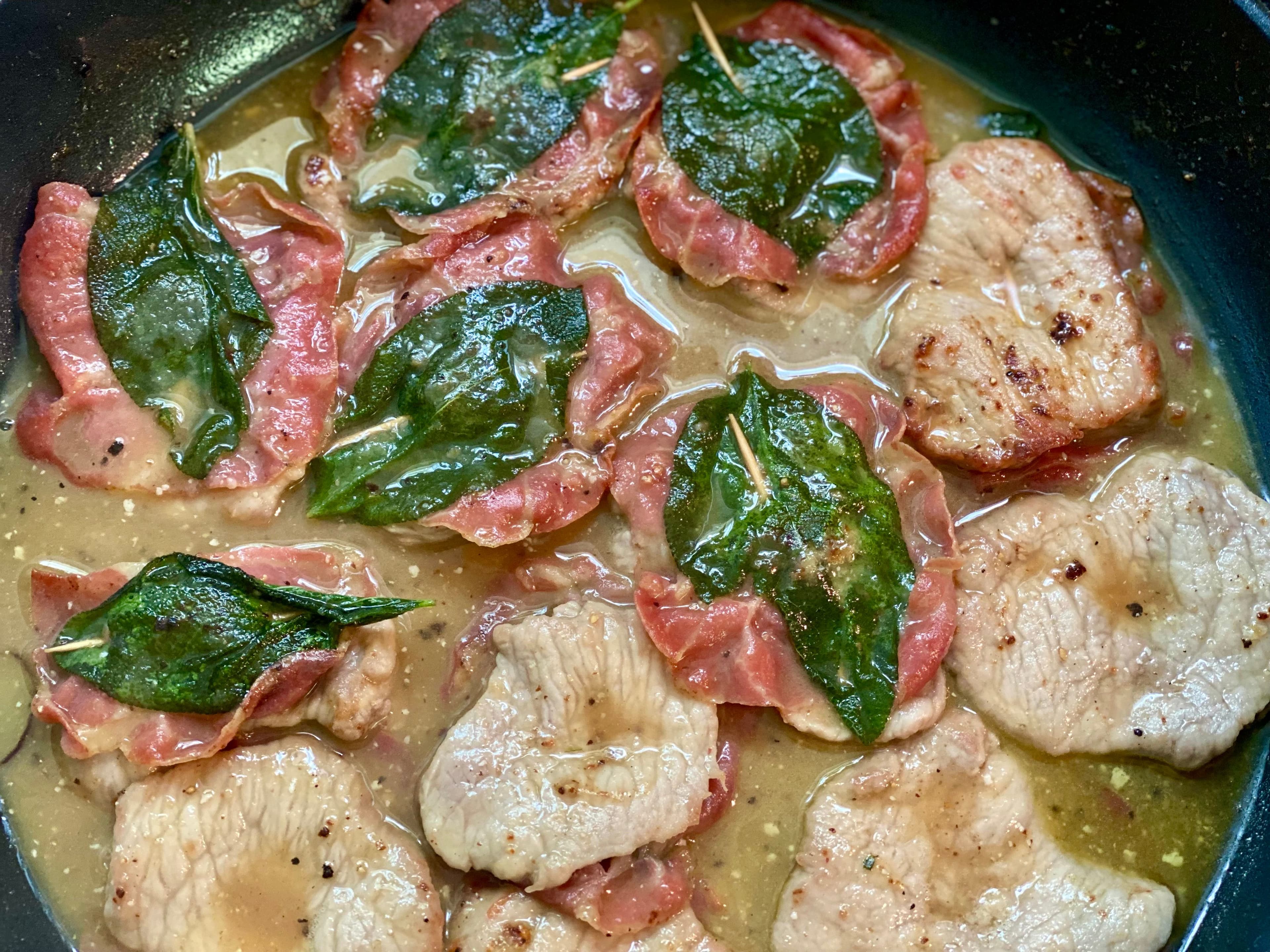 a frypan with the saltimbocca cooking in wine